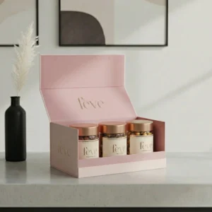 Elegant fève luxury gift box in blush pink featuring three gourmet nut jars with gold lids, displayed on a minimalist stone countertop.