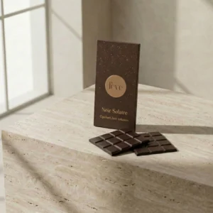 Fève Noir Solaire dark chocolate with orange zest infusion. Artisan dark chocolate bar in luxury gold-foiled packaging on a stone pedestal, high-end gourmet confectionery branding.